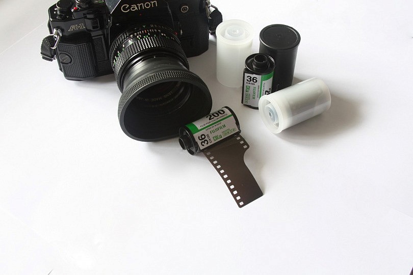 Vista superior de una cámara analógica retro, un carrete negativo, un  pasaporte y un cuaderno sobre una mesa de madera